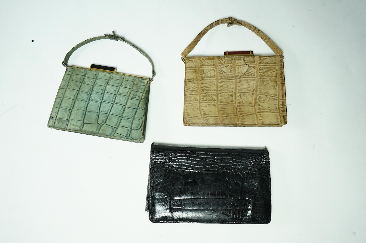 Three stylish Art Deco ladies handbags. A black crocodile clutch bag with an MMW monogram and silver mounted edge and two smaller handbags, one green the other brown, both faux crocodile with stylish bakelite clasps. Clu